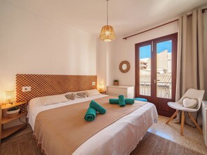 Ein Hotelzimmer mit einem Bett, einem Sessel, einem Fenster, einem an der Wand befestigten Spiegel und einem kleinen Tisch mit einer Pflanze.