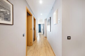 Un pasillo con puertas de madera, un cuadro enmarcado a la izquierda y un interruptor de luz a la derecha.