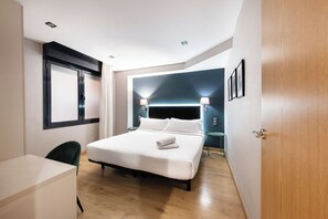 Ein modernes Hotelzimmer mit Bett, Nachttischen, einem Schreibtisch und einem Fenster.