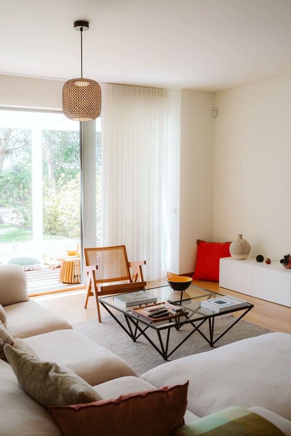 Een moderne woonkamer met een bank, een salontafel, een stoel en een rode kussens.