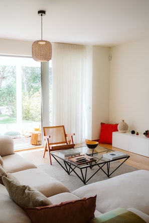 Una sala de estar moderna con un sofá, una mesa de centro, una silla y un cojín rojo.