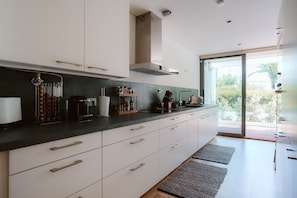 Una cocina moderna con armarios blancos, encimera negra y vistas a través de un ventanal.