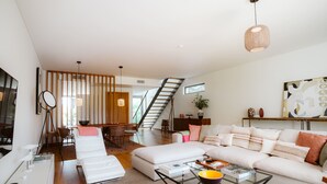 Ein modernes Wohnzimmer mit einer Couch, einem Couchtisch und einer Treppe, die in einen oberen Bereich führt.