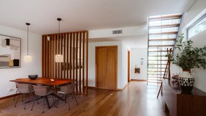 Ein modernes Interieur mit einem Holzespeisetisch, Stühlen, einer Wandverkleidung und einer Treppe mit Aussicht.