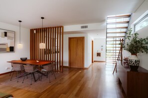 Een modern interieur met een houten eettafel, stoelen, een decoratieve wand en een trap met uitzicht.