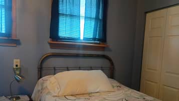 Una camera da letto con un letto, un comodino, una finestra con tende e una porta.