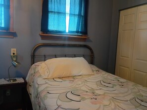 A bedroom with a bed, a bedside table, a window with blinds, and a door. - The Patriot on old Route 66 40 minutes from St Louis Mo. or Springfield, Il (Staunton)