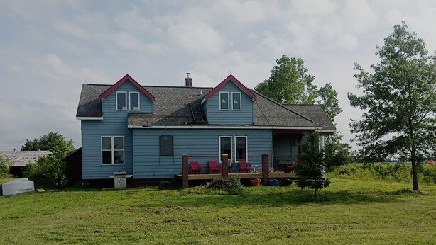A two-story house with a porch, a chimney, and a grassy yard.