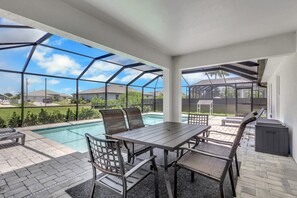 Eine überdachte Terrasse im Freien mit Pool, Sitzgelegenheiten und Blick auf die Nachbarschaft.