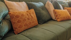 A green sofa with multiple cushions in various colors and patterns. - Villa les pins (Saint-Georges-de-Didonne)