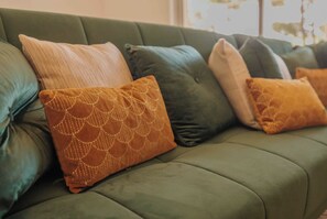 A green sofa with multiple cushions in various colors and patterns. - Villa les pins (Saint-Georges-de-Didonne)