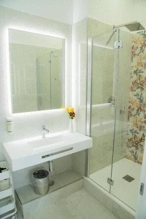 Un baño con lavamanos blanco, espejo y ducha.