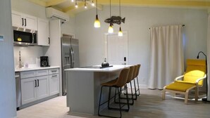 Une cuisine moderne avec des meubles blancs, un îlot central et des tabourets de bar.