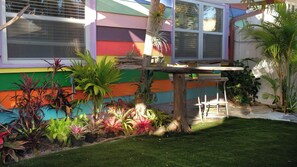 A colorful house with a small garden, a wooden table, and chairs. - Tropical Beach Cottage-Steps to the Beach-Short Walk to Siesta Key Village (Siesta Key)