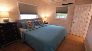 Une chambre à coucher avec un lit, une commode, des lampes de chevet et une porte.