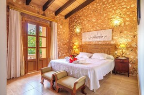 A bedroom with a large bed, a wooden headboard, a nightstand, and a bench. - Son Julia de sa Torre by Interhome (Porreres)