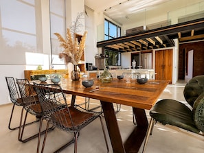 A dining area with a wooden table, metal chairs, and a vase with dried plants.