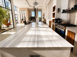 A modern kitchen with a large island, built-in appliances, and a view to the outside.
