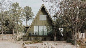 Una casa a forma di A con tetto spiovente, un portico, ampie finestre e un cortile recintato.