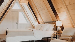 Una camera da letto mansardata accogliente, con un letto, una poltrona e una lampada.