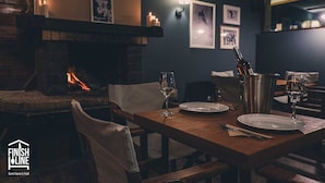 A cozy dining area with a fireplace, wooden table, and chairs. - Finish Line Guest House (Samokov)
