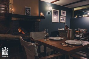 Un rincón comedor acogedor con chimenea, mesa de madera y sillas.