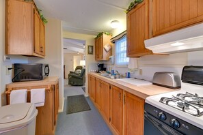 A compact RV kitchen with wooden cabinets, a gas stove, a toaster, and a microwave. - Unwind in the heart of the FingerLakes (Dundee)