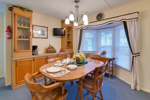 A dining area with a wooden table, chairs, a television, a fire extinguisher, and a window with blinds. - Unwind in the heart of the FingerLakes (Dundee)