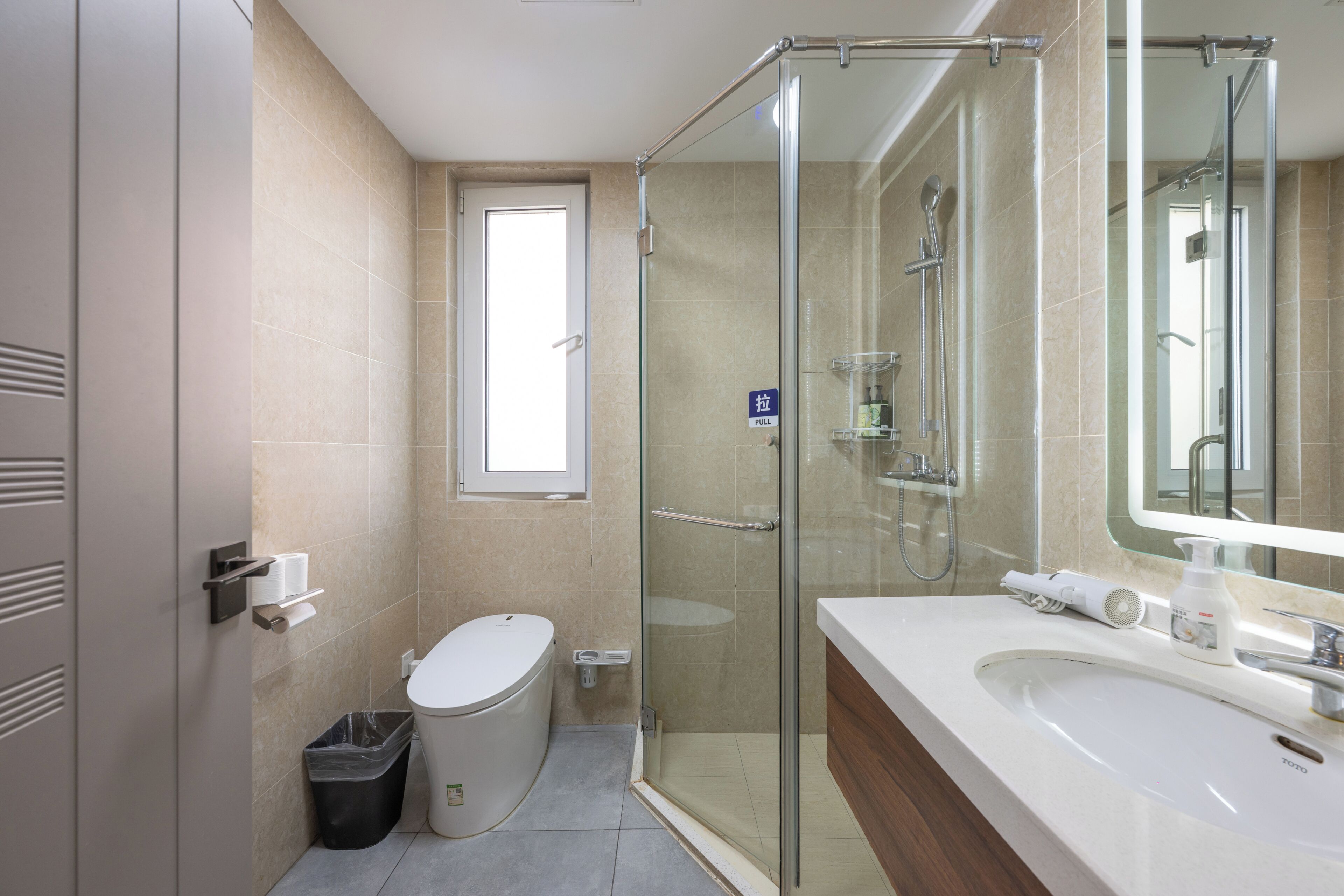 Un baño moderno con cabina de ducha de vidrio, inodoro, lavabo y espejo.