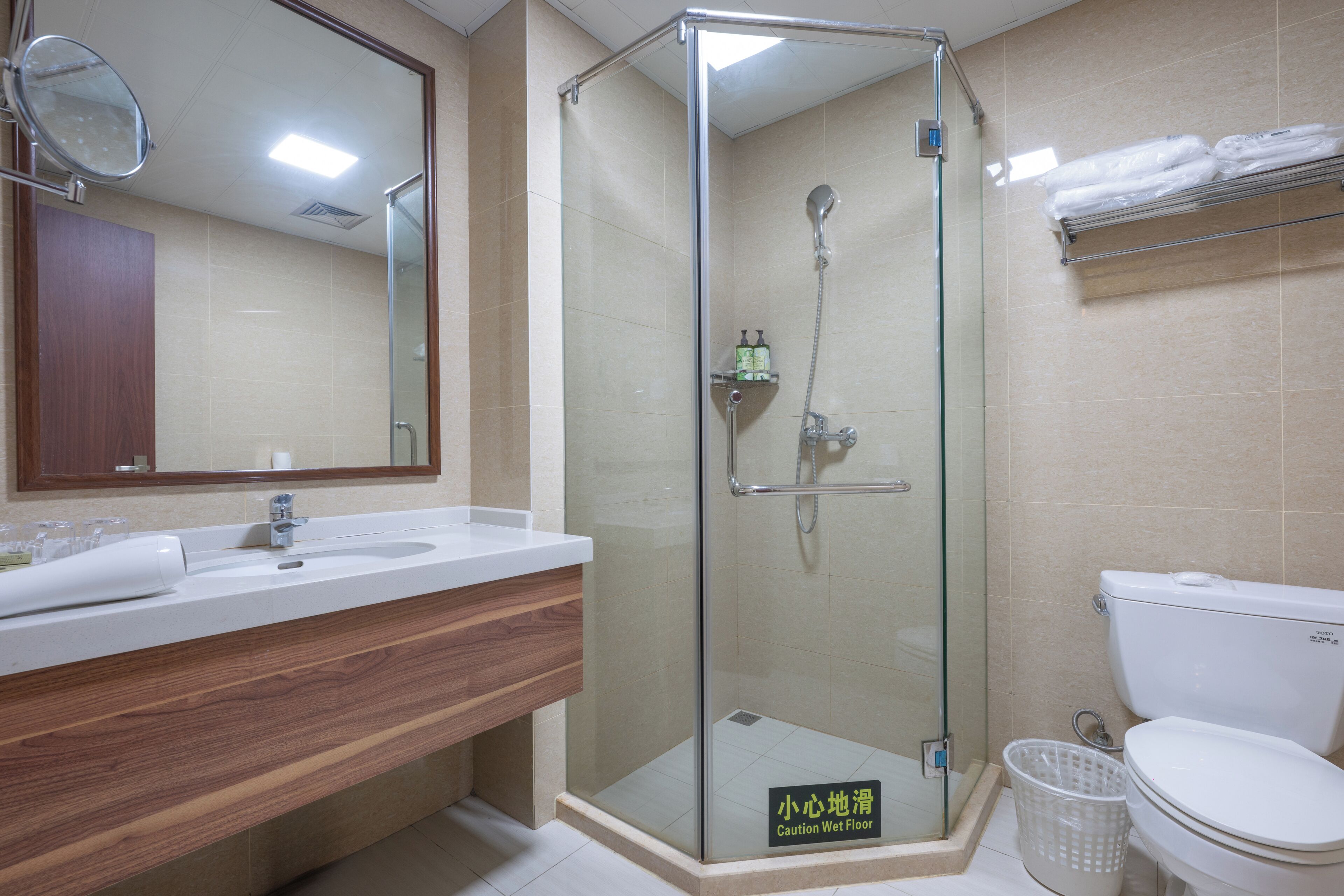 A bathroom with a glass-enclosed shower, a sink with a wooden vanity, and a toilet.