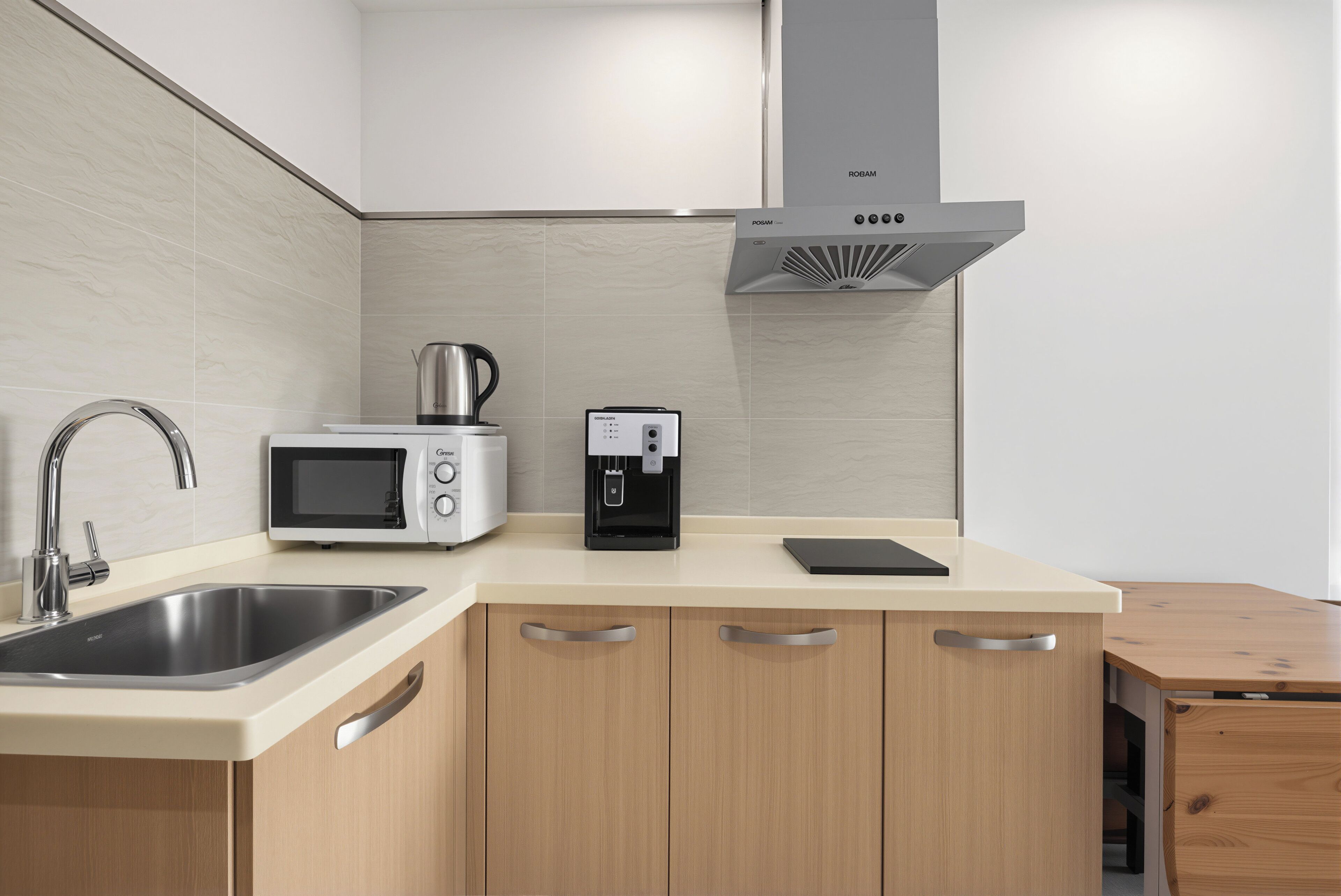 A modern kitchen with a stainless steel sink, a microwave, a coffee maker, and wooden cabinets.