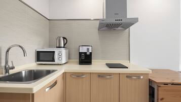 A modern kitchen with a stainless steel sink, a microwave, a coffee maker, and wooden cabinets.