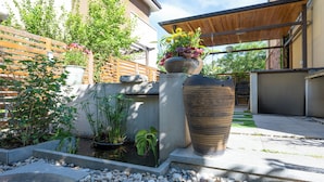 A garden with a koi pond, potted plants, and a large decorative vase.