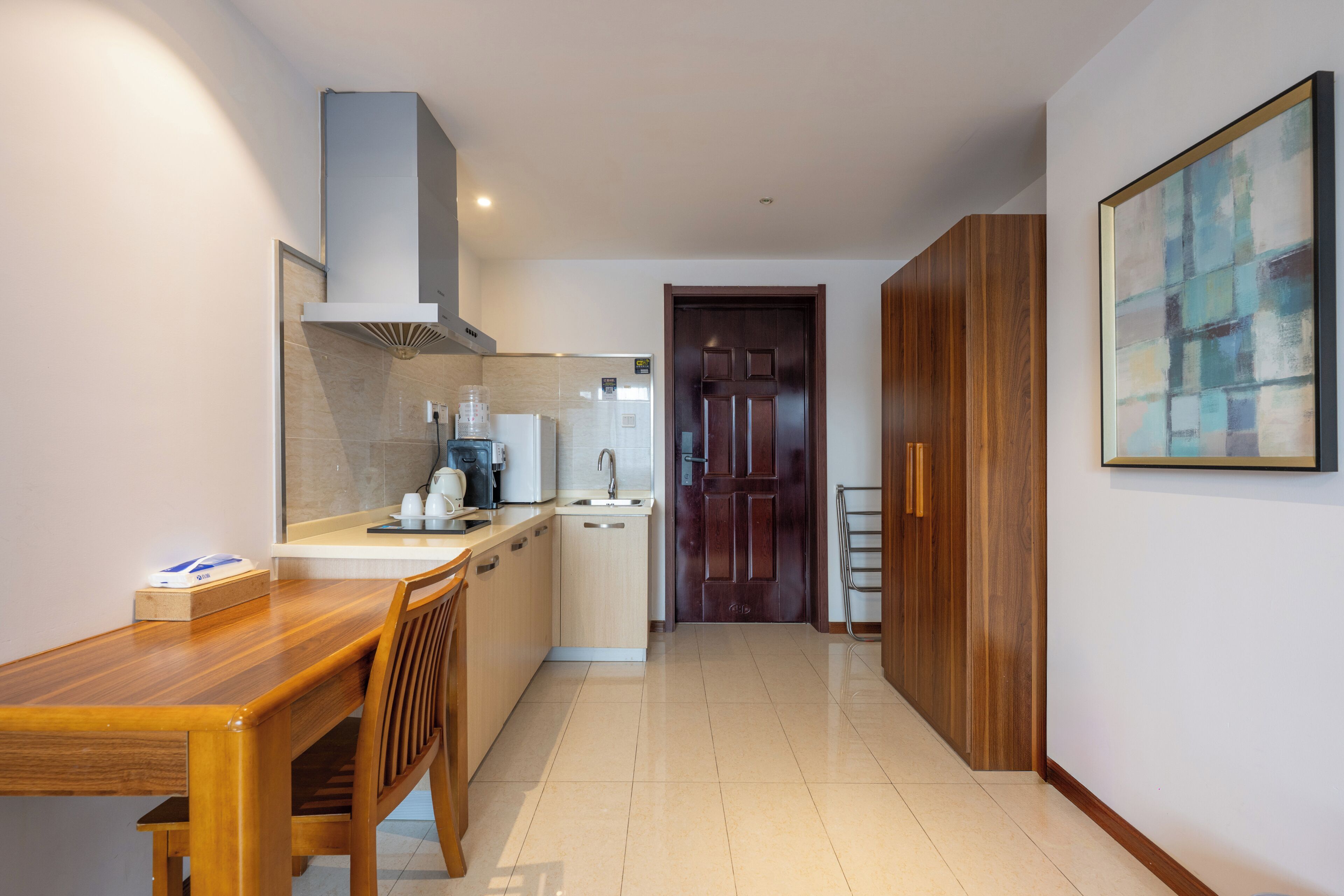 A modern kitchen with a wooden dining table, a built-in oven, and a coffee machine.