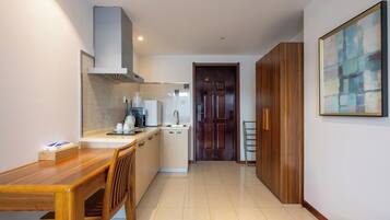 A modern kitchen with a wooden dining table, a built-in oven, and a coffee machine.