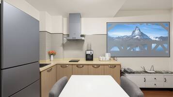 A modern kitchen with a refrigerator, coffee maker, and a large window with a mountain view.