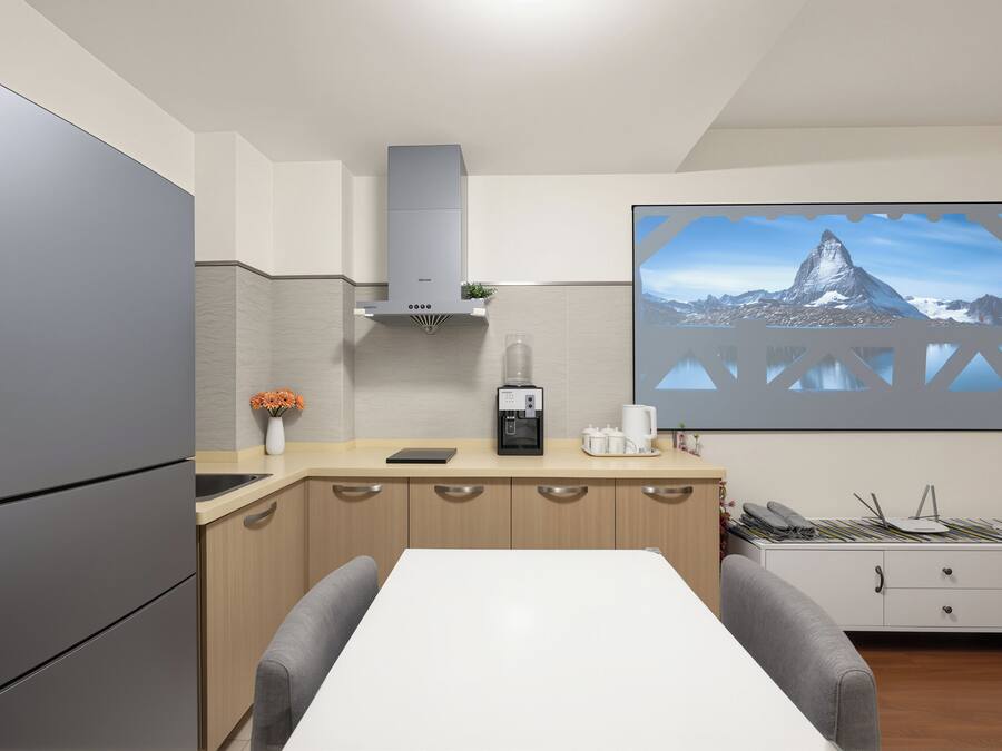 A modern kitchen with a refrigerator, coffee maker, and a large window with a mountain view.