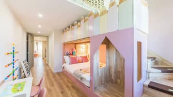 A child's bedroom with a bunk bed, a play area with toys, and a staircase.