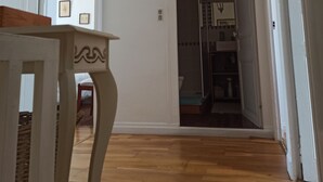 Een hal met houten vloer, een witte deur en een glazen deur naar een badkamer.