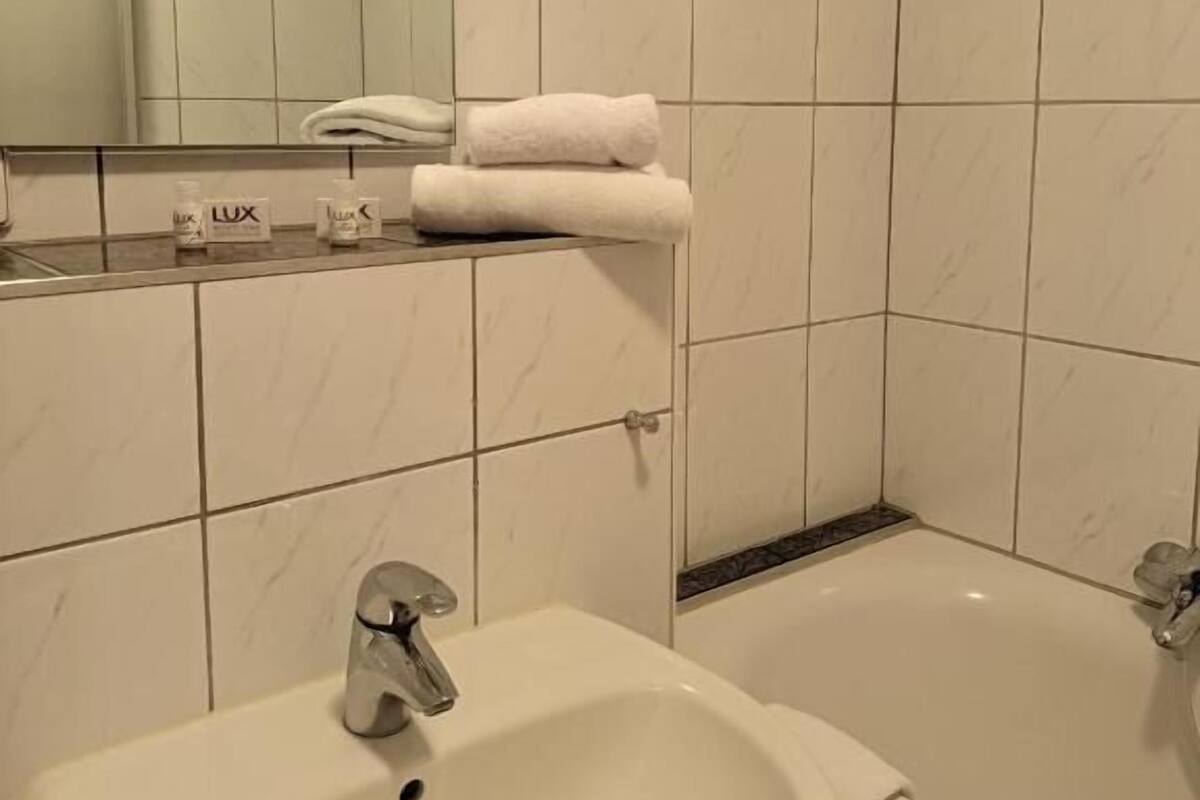 A bathroom with a sink, a mirror, a bathtub, and a towel rack.