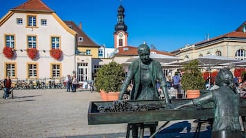 A public square with a statue, buildings, and a clock tower.