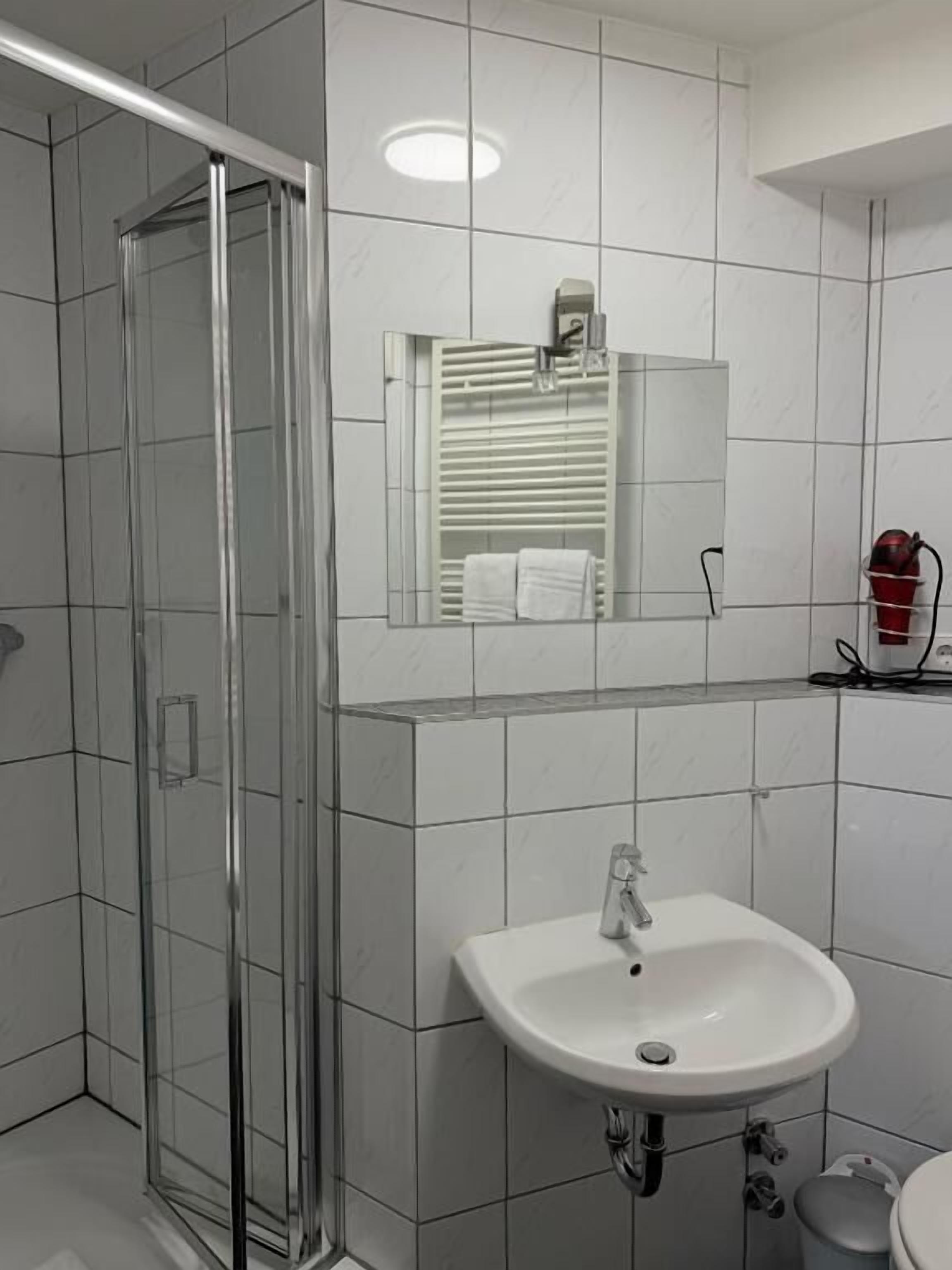 A bathroom with a glass shower enclosure, a white sink, and a mirror above the sink.