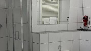 A bathroom with a glass shower enclosure, a white sink, and a mirror above the sink.