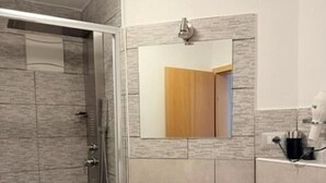 A bathroom with a shower, sink, and mirror. - Hotel Altavilla (Schwetzingen)