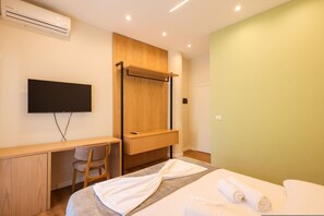 Une chambre d’hôtel moderne équipée d’un lit, d’un bureau, d’une chaise, d’une télévision et d’une armoire intégrée.
