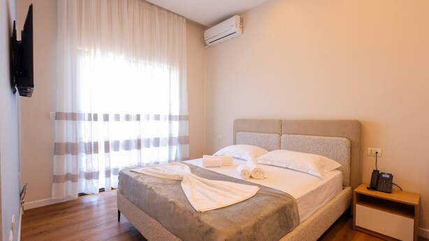 Ein Hotelzimmer mit einem Bett, einem Nachttisch mit Telefon und einer Klimaanlage.