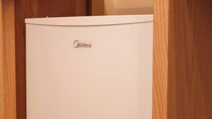 Ein weißes Midea-Gerät, vermutlich ein Kühlschrank, in einem Holzkasten.