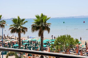 Ein Strand mit Palmen, Sonnenschirmen und Liegestühlen.