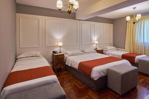 Ein Hotelzimmer mit drei Betten, Holzboden und einem Kronleuchter.