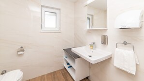 A bathroom with a white sink, a mirror, a towel rack, and a window. - Altiora Prestige Residence 303 (Gradac)